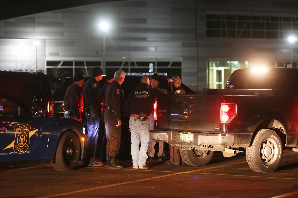 Policías conversan la madrugada del domingo en una localidad de Kalamazoo, Michigan, donde ocurrió la tragedia. (Foto Prensa Libre: AP).