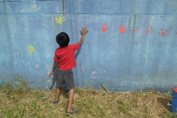 Uno de  los niños de la colonia El Limón plasma sus huellas en un mural dedicado a la paz.