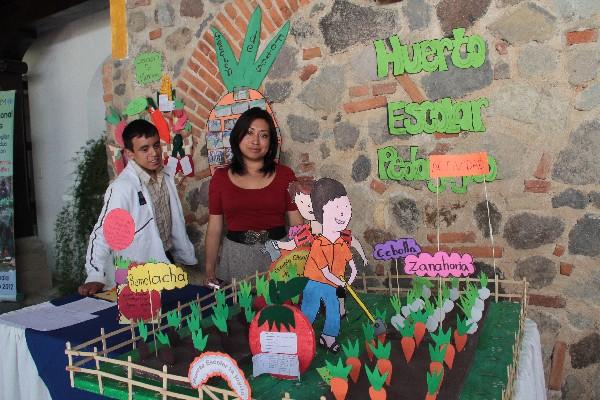 Los técnicos agrícolas Francis Tum y  Sadi García  muestran maqueta  que representa huerto  escolar.