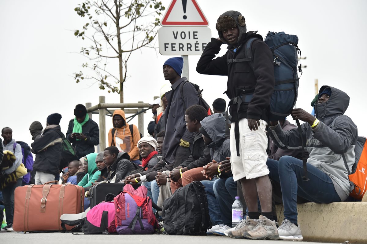 Migrantes en Calais esperan el transporte que los llevará a su nuevo refugio. (Foto Prensa Libre: AFP).