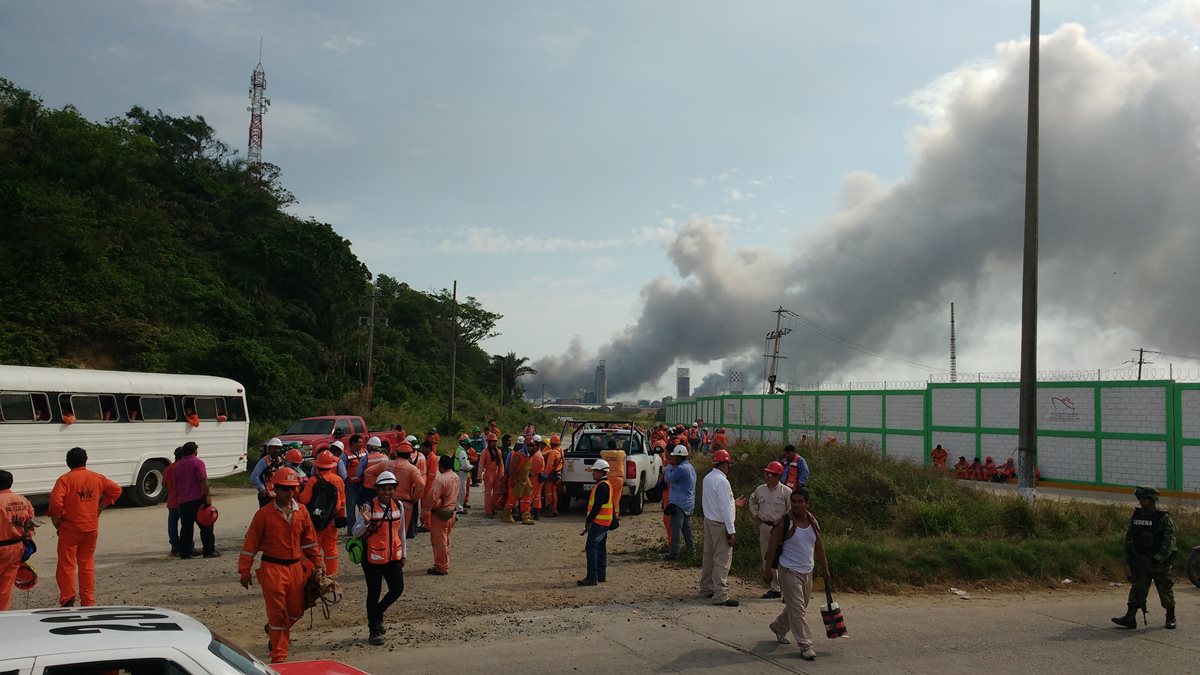 Trabajadores son evacuados después de la fuerte explosión en la planta petrolera. (Foto Prensa Libre: AFP).