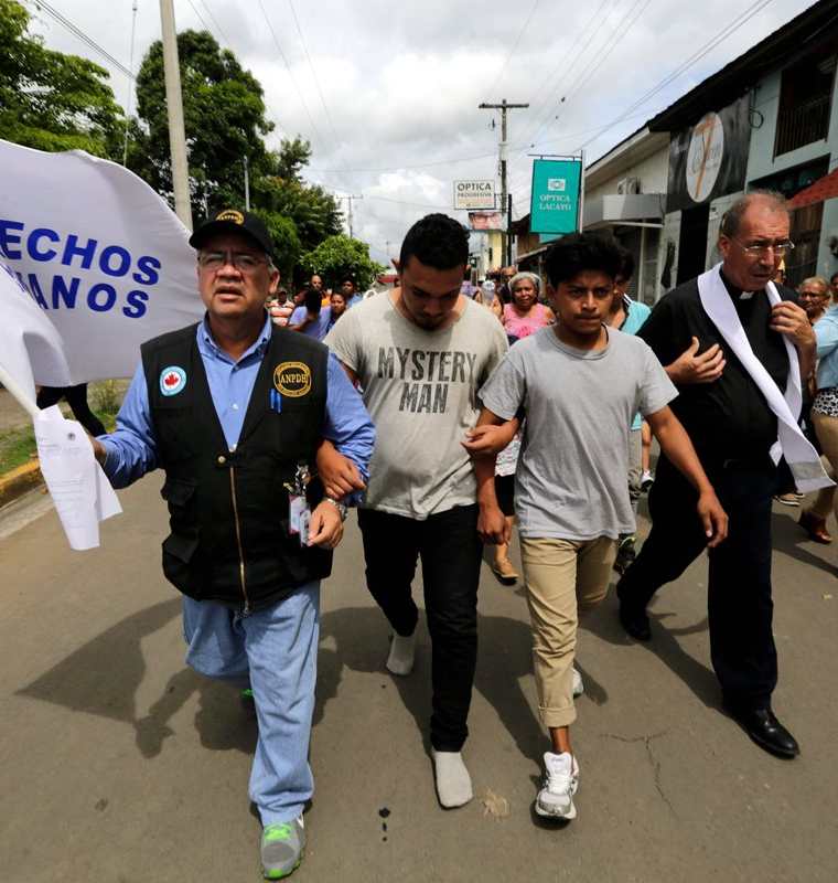 Dos hombres (c) -que habían sido arrestados en recientes protestas- caminan junto a un sacerdote y integrante de la Asociación Nicaragüense de Derechos Humanos (ANPDH) después de ser liberados de la cárcel en Masaya, Nicaragua. (EFE).