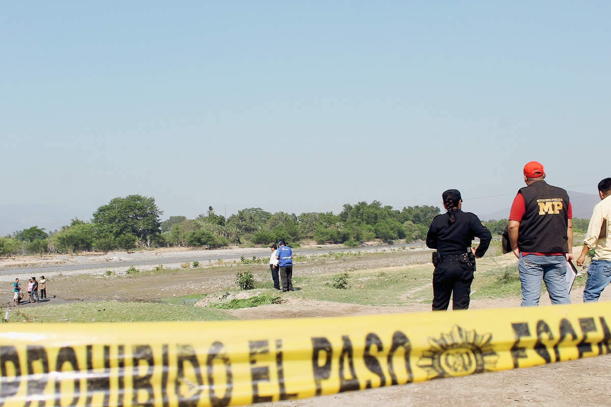 Fiscales del  Ministerio Público recogen evidencias en lugar donde pescadores hallaron el cadáver de un joven, en el río Motagua, en Zacapa. (Foto Prensa Libre: Víctor Gómez)