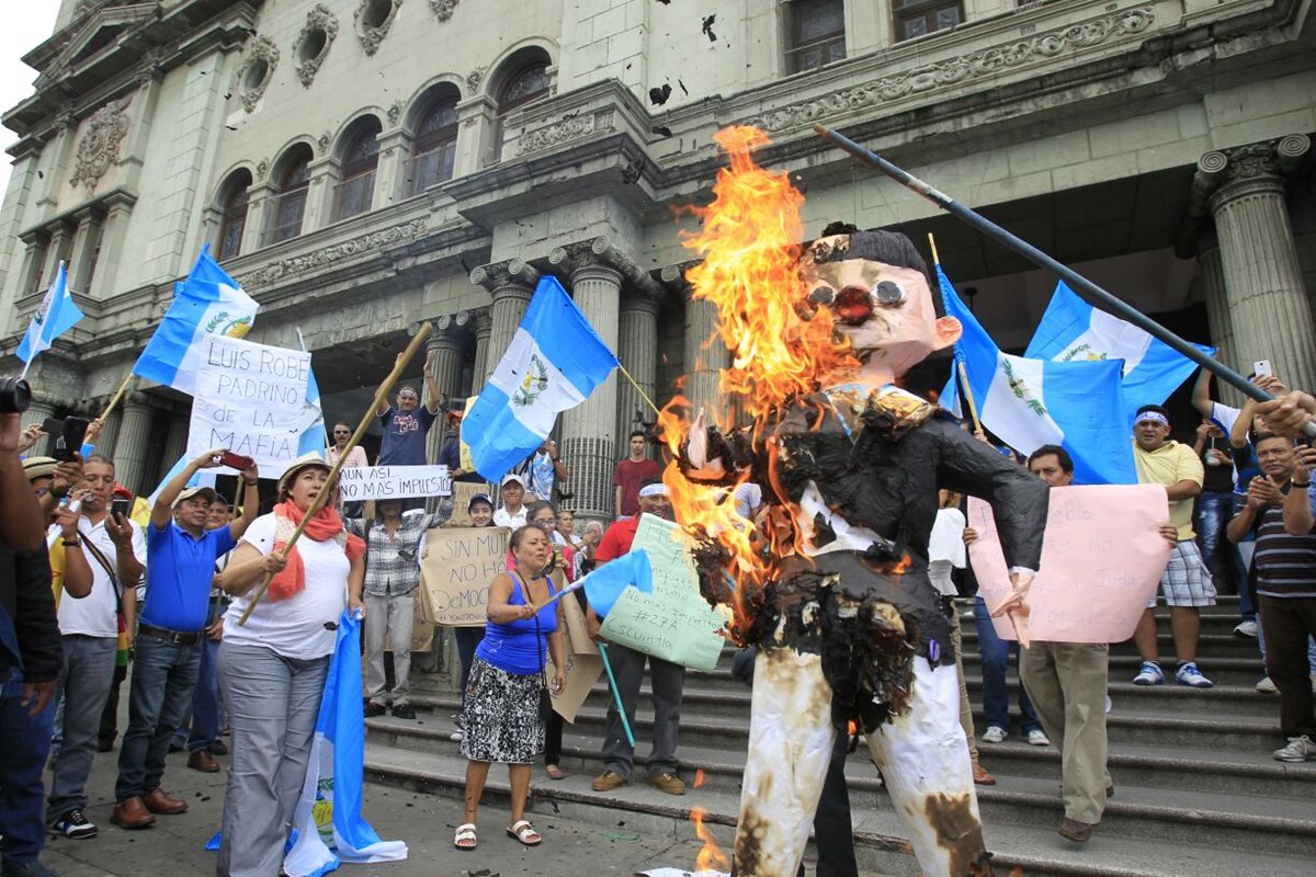 Una piñata que simula al presidente Jimmy Morales es quemada frente al Palacio Nacional de la Cultura. (Foto Prensa Libre: Paulo Raquec)