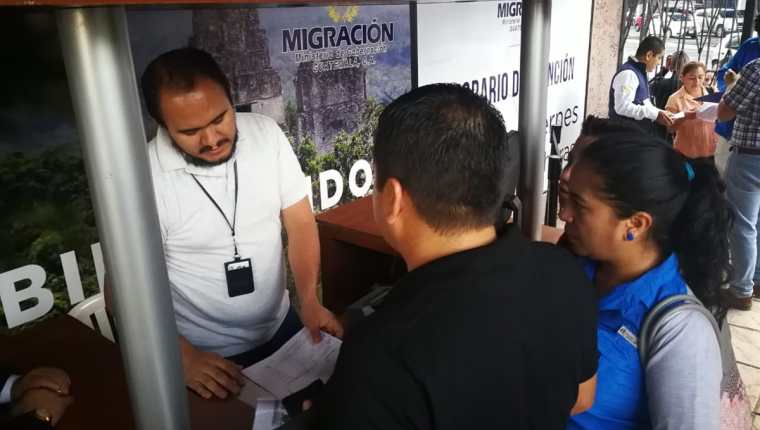 Personal de Migración entrega números a dos personas que llegaron a realizar su trámite. (Foto Prensa Libre: Estuardo Paredes)
