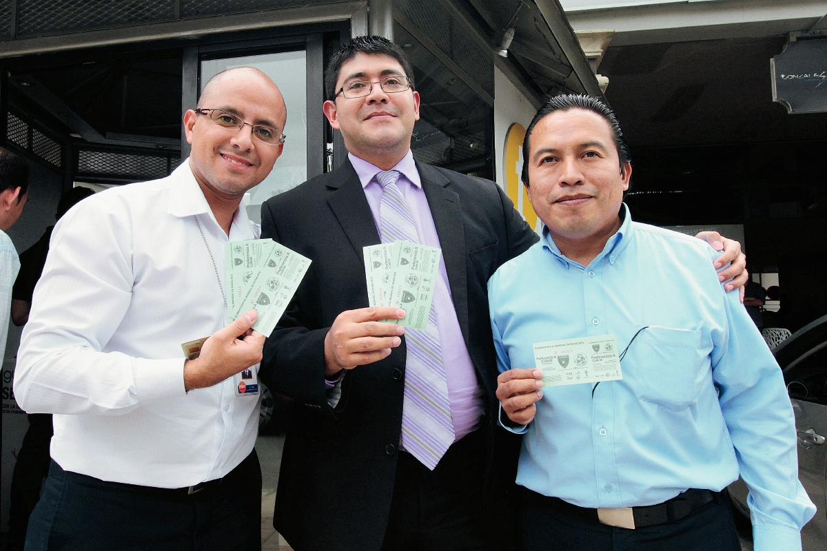 Tres aficionados posan orgullosos con sus entradas para el juego de mañana por la noche. (Foto Prensa Libre: Marcela Morales)