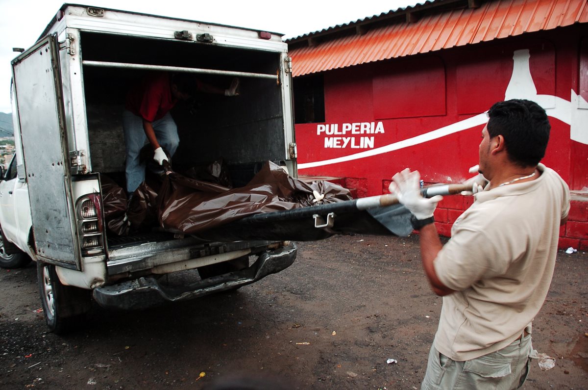 Especialistas trasladan los cadávers de los jóvenes asesinados en Honduras. (Foto Prensa Libre: AFP)