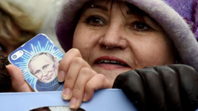 Una mujer sostiene una imagen del presidente ruso Vladimir Putin que lleva pegada a su celular. GETTY IMAGES