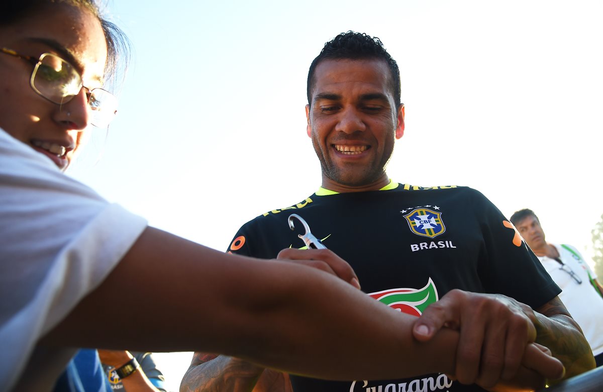 Dani Alves sonríe mientras le firma un autógrafo a un aficionado en UCLA después del entreno de Brasil. (Foto Prensa Libre: AFP)