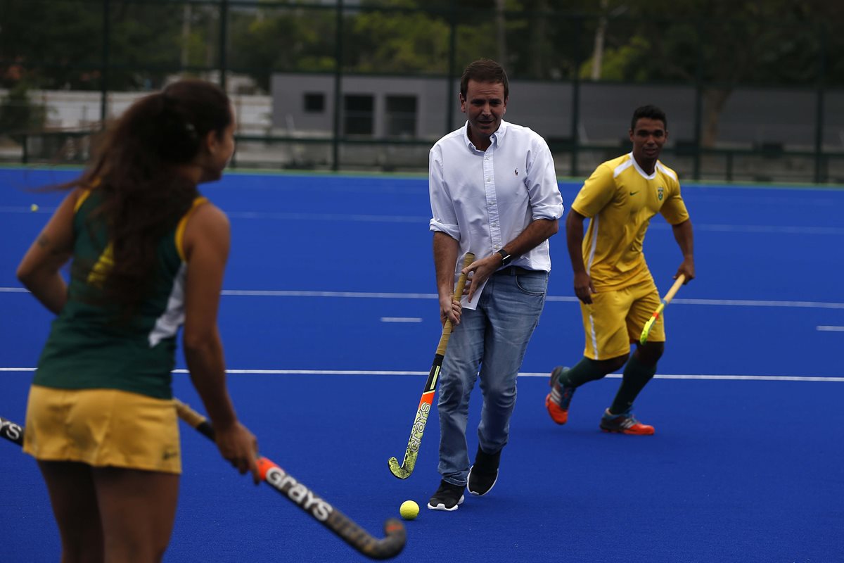 El alcalde de Rio, Eduardo Paes (c), juega con atletas de la selección brasileña de hockey durante una presentación en la cancha del complejo de Deodoro para los Juegos Olímpicos Río. (Foto Prensa Libre: EFE)