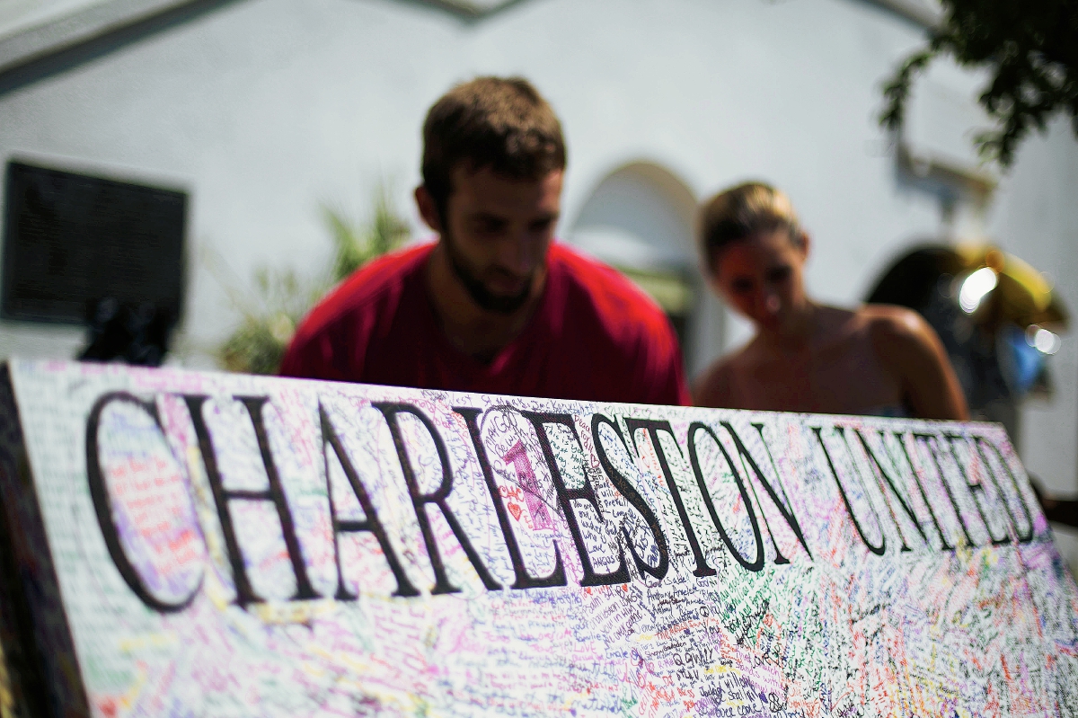 “Charleston unido” se lee en esta pancarta que un hombre sostiene en memoria de los nueve afrodescendientes que fueron asesinados la semana pasada en una iglesia. (Foto Prensa AP).