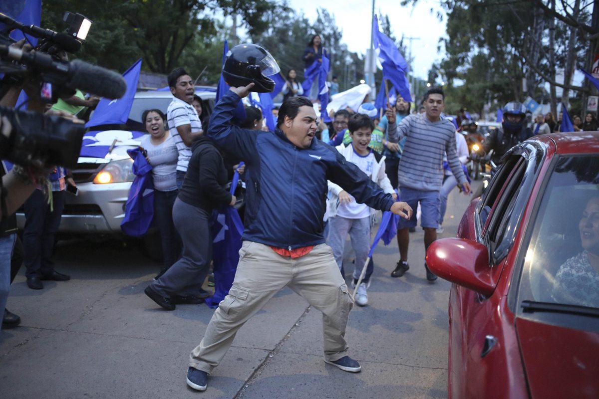 Simpatizantes del Partido Nacional de Honduras le arrebatan una bandera de la Alianza contra la Corrupción a personas que conducían en un vehículo durante una manifestación en Tegucigalpa. (Foto Prensa Libre: EFE)