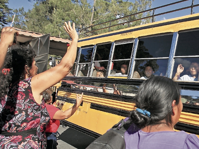 Menores trasladados del Hogar Seguro Virgen de la Asunción se despiden, desde el bus que los transporta, de familiares que llegaron a verificar que se encontraban bien.