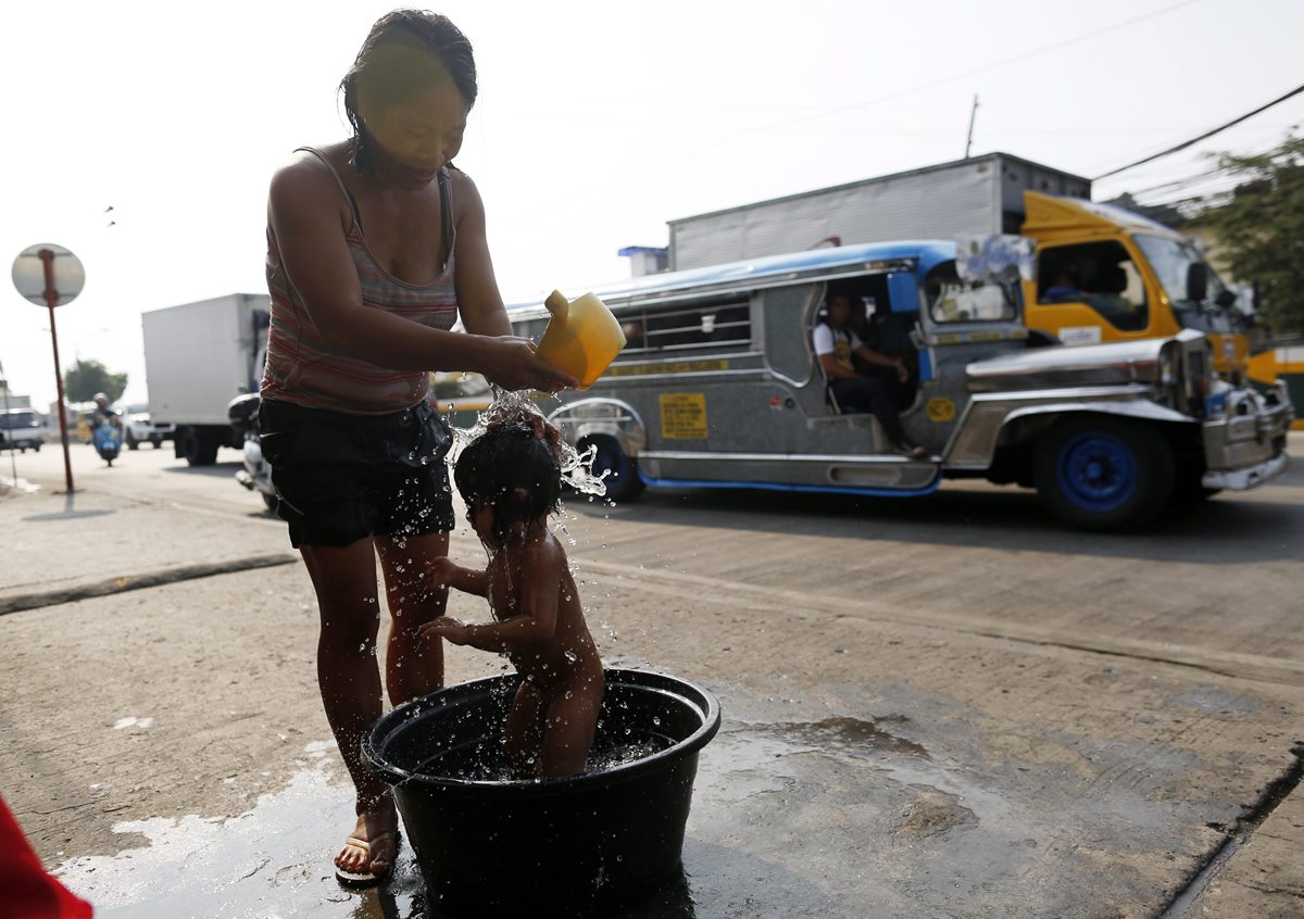 Una mujer refresca por el calor a su pequeño hijo en Manila, Filipinas. (Foto Prensa Libre: EFE).