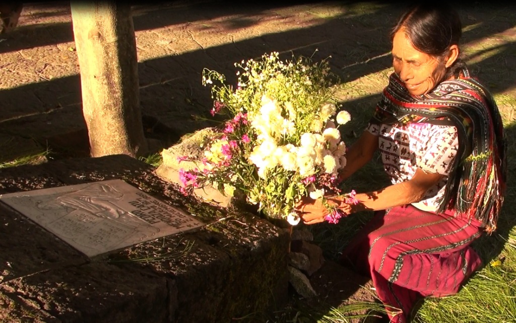 Mujer coloca flores en una placa en memoria de las víctimas en Santiago Atitlán, Sololá. (Foto Prensa Libre: Facebook).