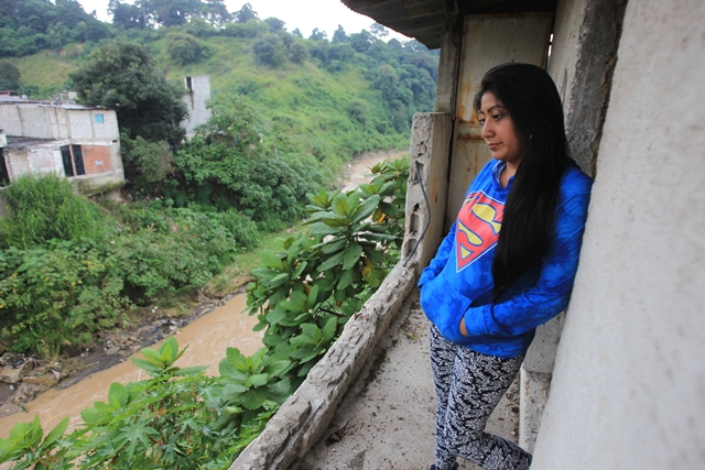 cINDY hERNÁNDEZ observa desde el segundo piso de su vivienda cómo crece el cauce del río Pinula debido a la intensa lluvia. En el 2013 la corriente destruyó el patio trasero y otras casas. (Foto Prensa Libre: Esbin García)