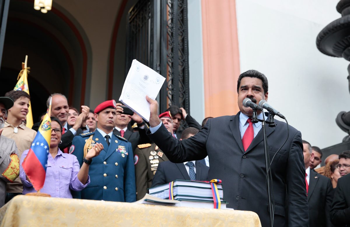 El presidente Nicolás Maduro habla a simpatizantes desde el Palacio de Miraflores mientras sostiene una copia del presupuesto que él aprobó sin consulta del Congreso. (Foto Prensa Libre: EFE).