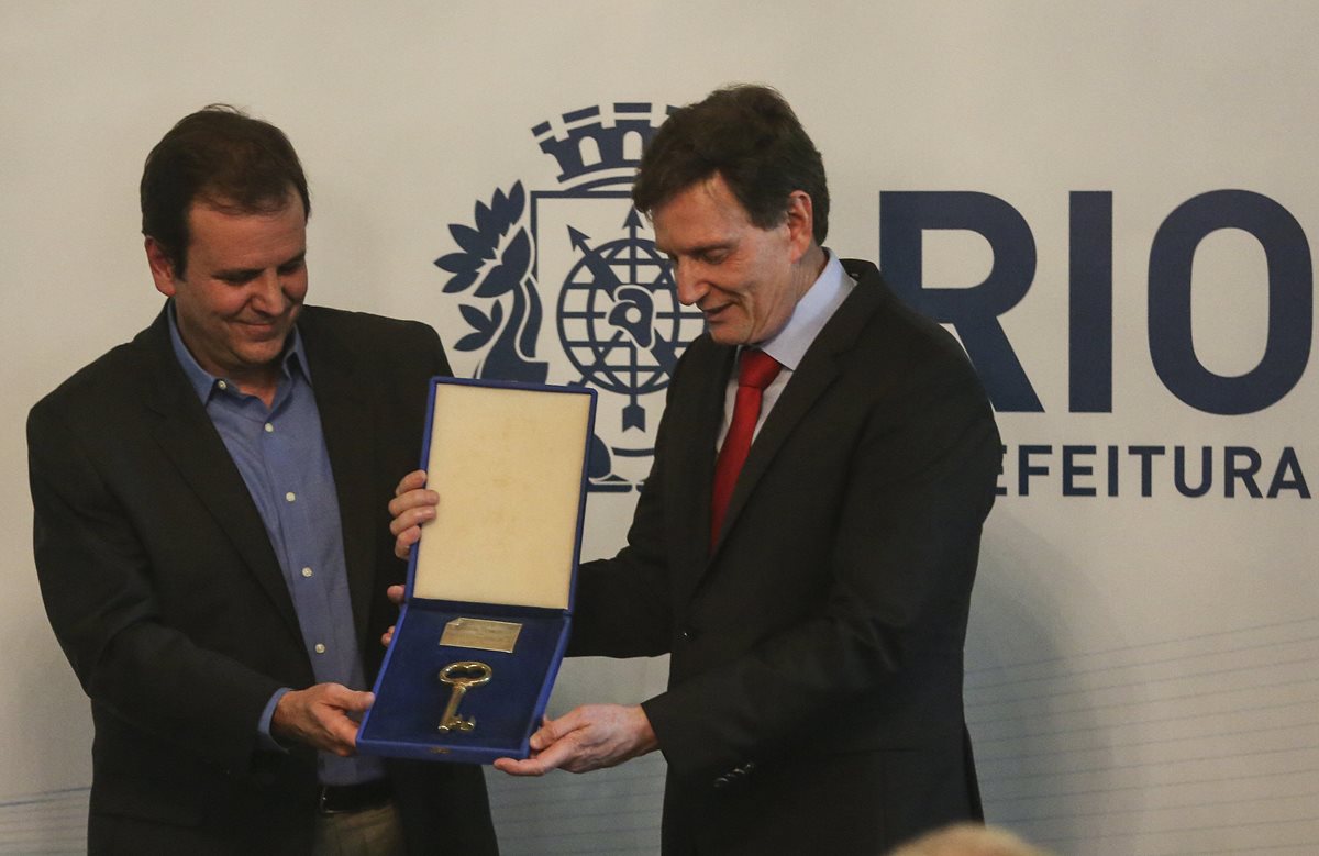 El ex alcalde de Río de Janeiro, Euardo Paes, entrega la llave de la ciudad al senador Marcelo Crivella, quien asumió como alcalde de Río de Janeiro. (Foto Prensa Libre: EFE)
