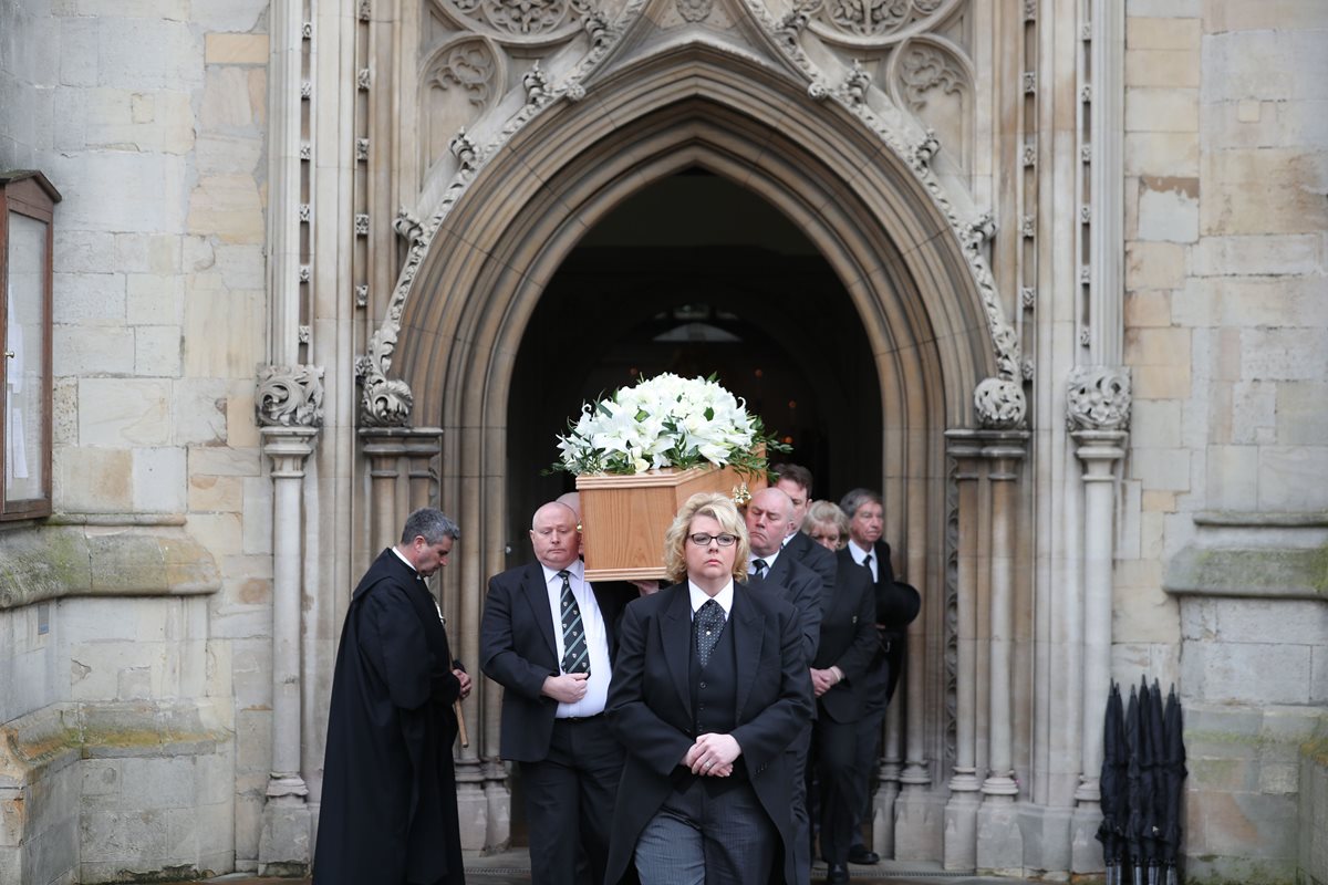 Personal del colegio Gonville & Caius cargan el féretro del científico británico Stephen Hawking después del funeral en la iglesia de la Gran Santa María, en Cambridge, Inglaterra. (Foto Prensa Libre: AFP).