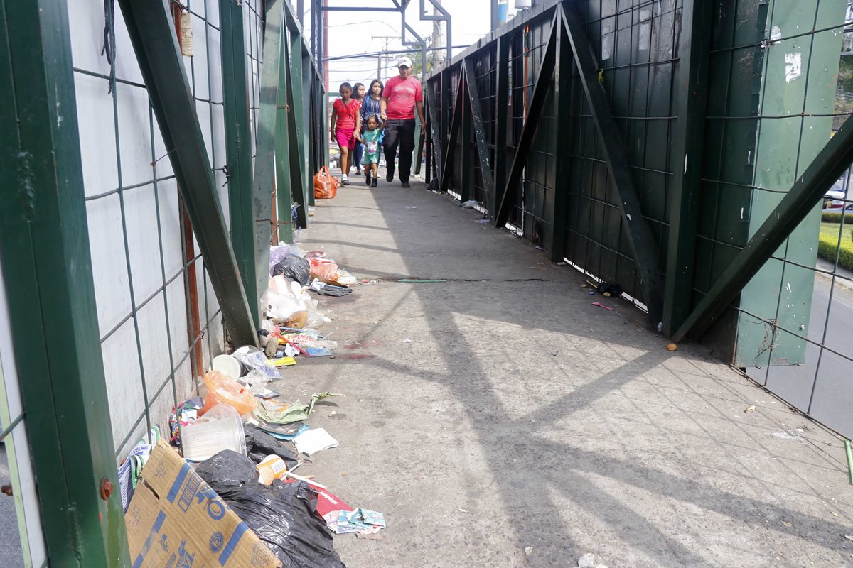 Algunos peatones usan la pasarela, la cual luce llena de basura. (Foto Prensa Libre: Rolando Miranda).