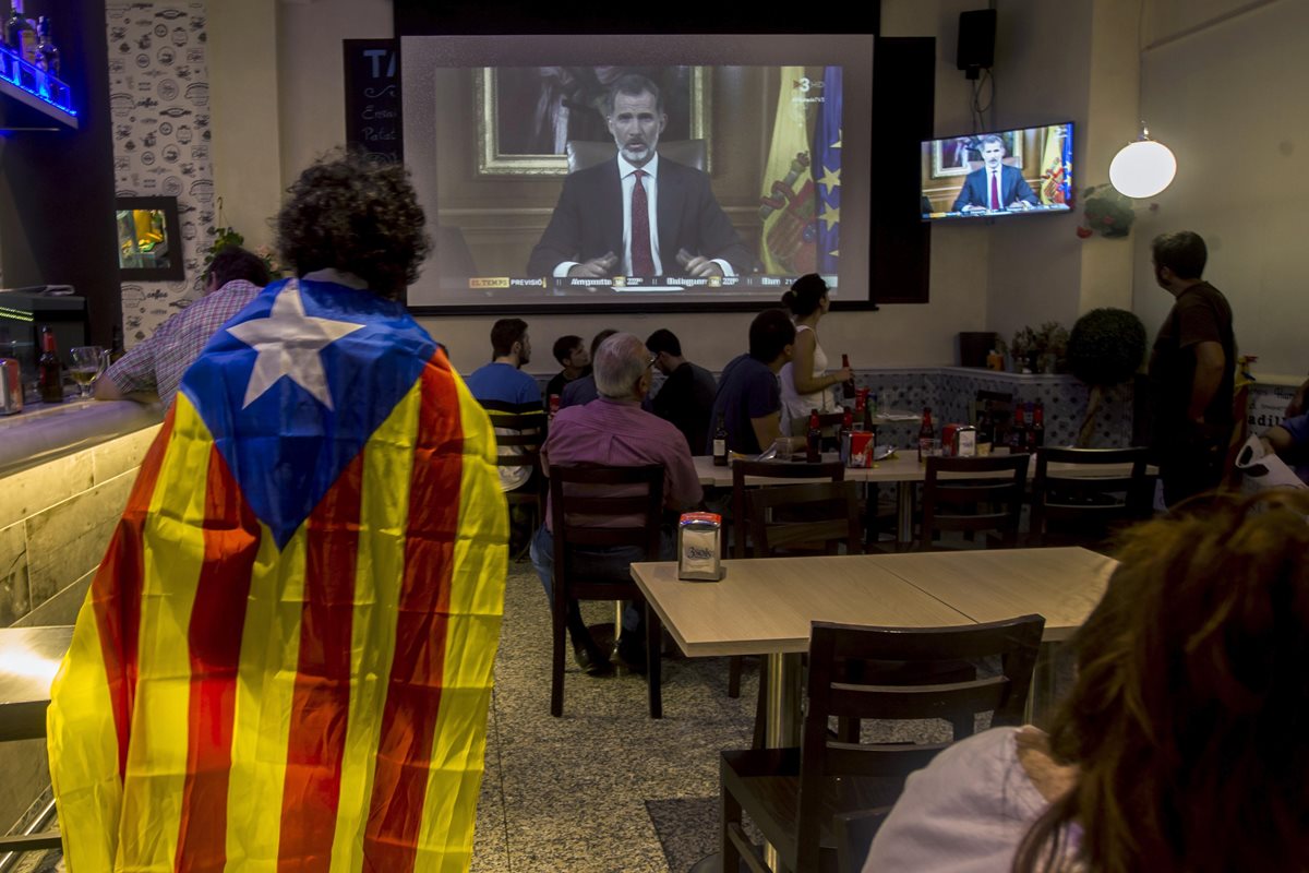 Varias personas miran el discurso del Rey Felipe VI durante la jornada de paro general en España. (Foto Prensa Libre: EFE)