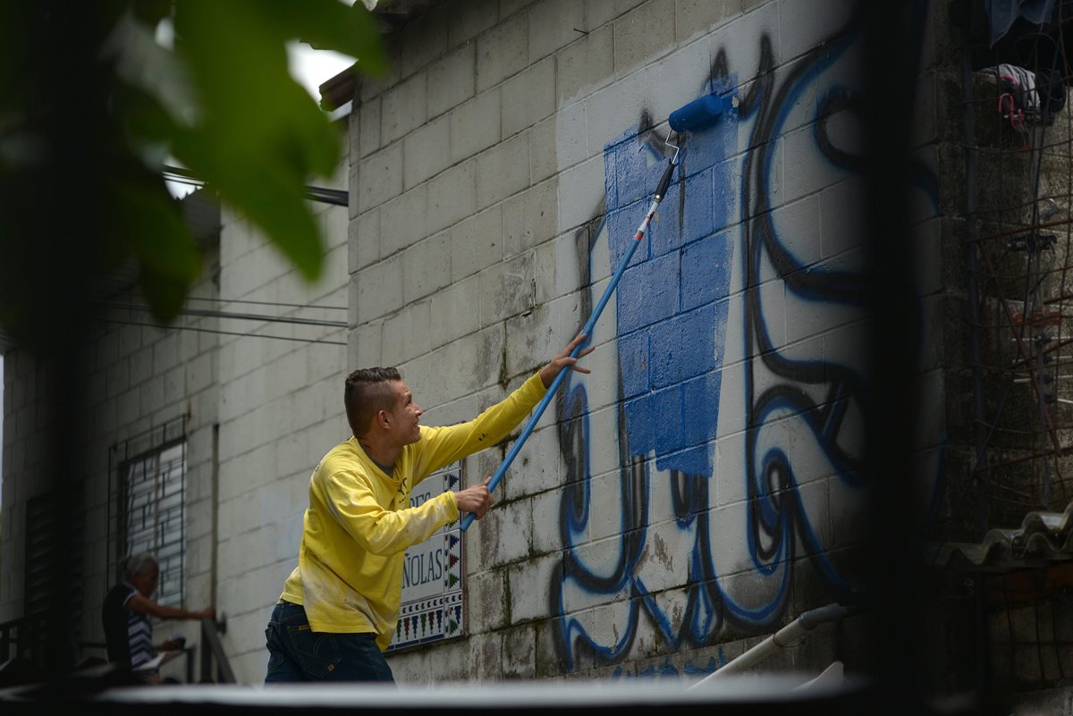 Un hombre participa en la jornada de "megalimpieza" de grafitis de pandillas en El Salvador. (Foto Prensa Libre: AFP).