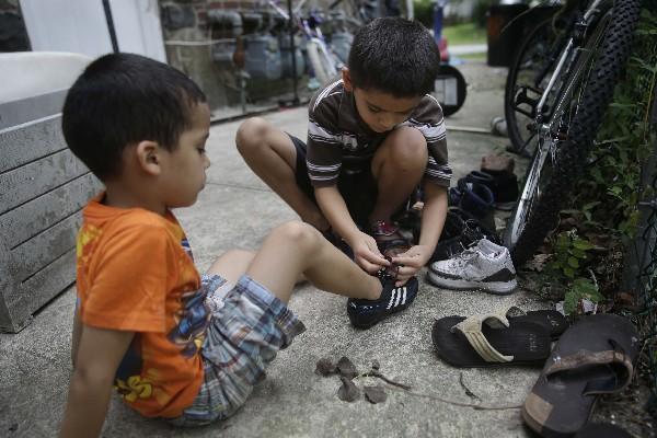 Kevin Torres, de 7 años, ayuda a Darwin Ruiz, 7, mientras juegan en una vivienda de Nueva York. (Foto Prensa Libre: AP).