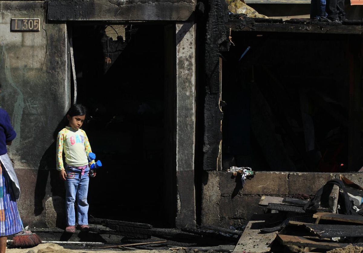 Niña recostada en una de las paredes que no tuvo mayores daños por el fuego que consumió 30 viviendas. (Foto Prensa Libre: Carlos Hernández)