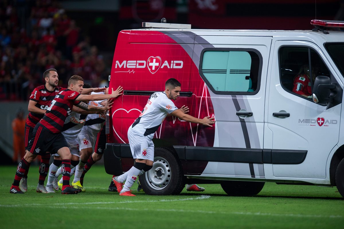 Los jugadores de Flamengo y Vasco tuvieron que empujar la ambulancia. (Foto Prensa Libre: AFP)