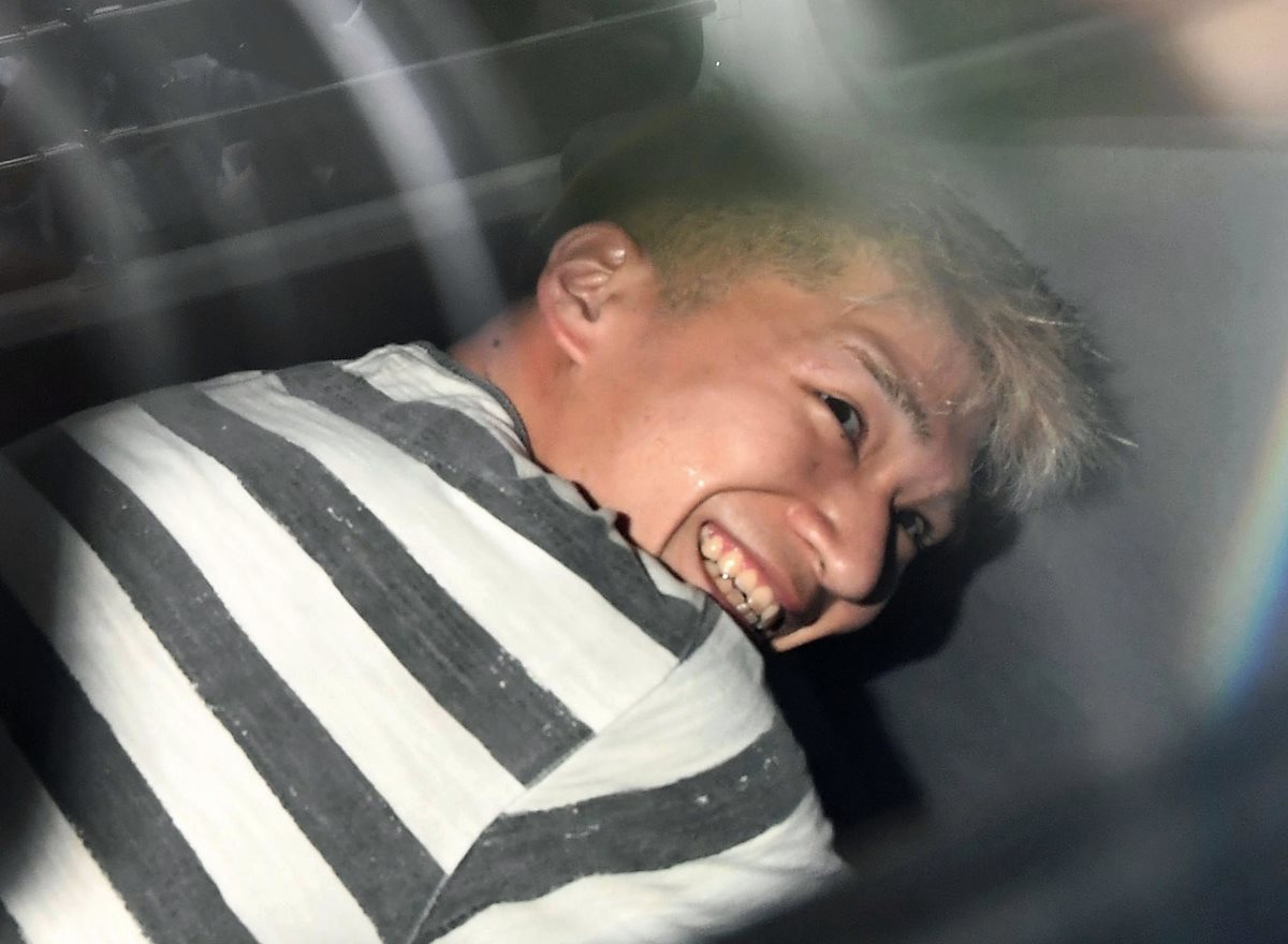 Satoshi Uematsu, autor confeso de 19 discapacitados en Japón, sonríe en una patrulla policial mientras es trasladado a la Fiscalía de Tokio. (Foto Prensa Libre: AP).