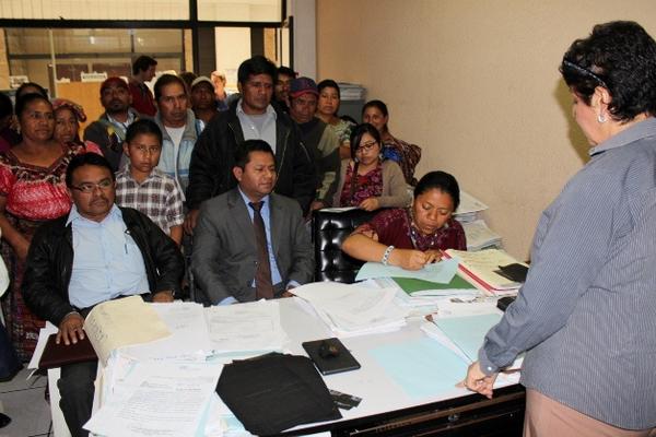 Aura Chávez, sindicada de dos delitos, -sentada a la derecha- firma un documento en la sede del MP, en Santa Cruz del Quiché. (Foto Prensa Libre: Óscar Figueroa)