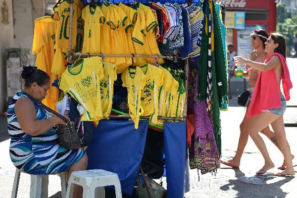 En Río de Janeiro una mujer vende playeras de las selecciones que participan en el Mundial de Fútbol. (Foto Prensa Libre: AFP)