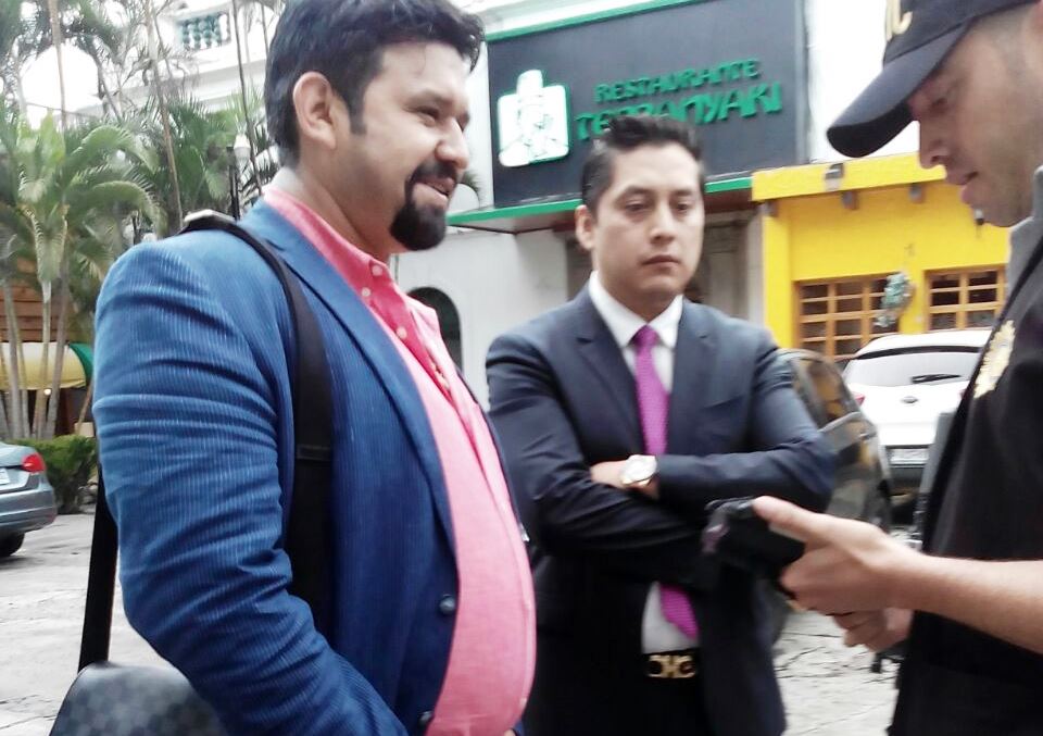 Un agente de la Policía procede a identificar al supuesto narcotráficante, Manuel Felipe Arenales Monroy, observa el abogado Mario Cano. (Foto Prensa Libre)