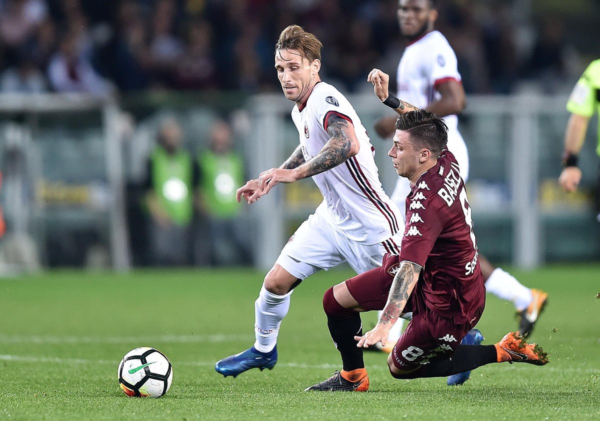 Lucas Biglia disputa un balón con Daniele Baselli en el partido entre el Milan y el Torino. (Foto Prensa Libre: EFE)