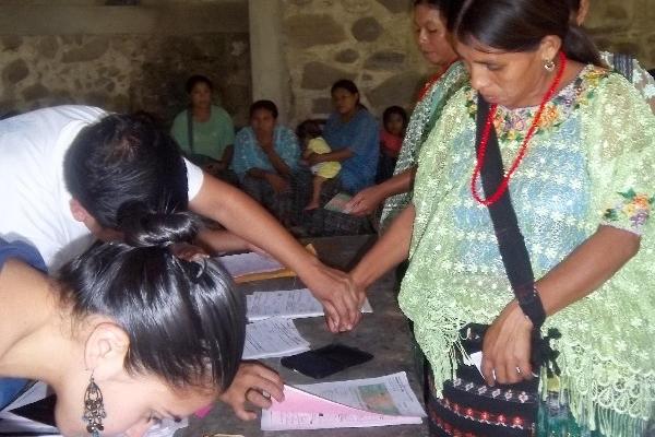 Una mujer recibe ayuda para estampar su huella para dejar constancia de que recibió Q800 para iniciar un micronegocio.