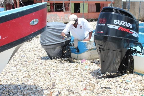 Lanchero de Puerto Barrios, Izabal,   recoge  el  duropor acumulado en las playas de la Bahía   de  Amatique.