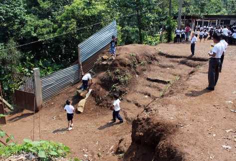 Estudiantes juegan en patio de  escuela, la cual no cuenta con muro perimetral.