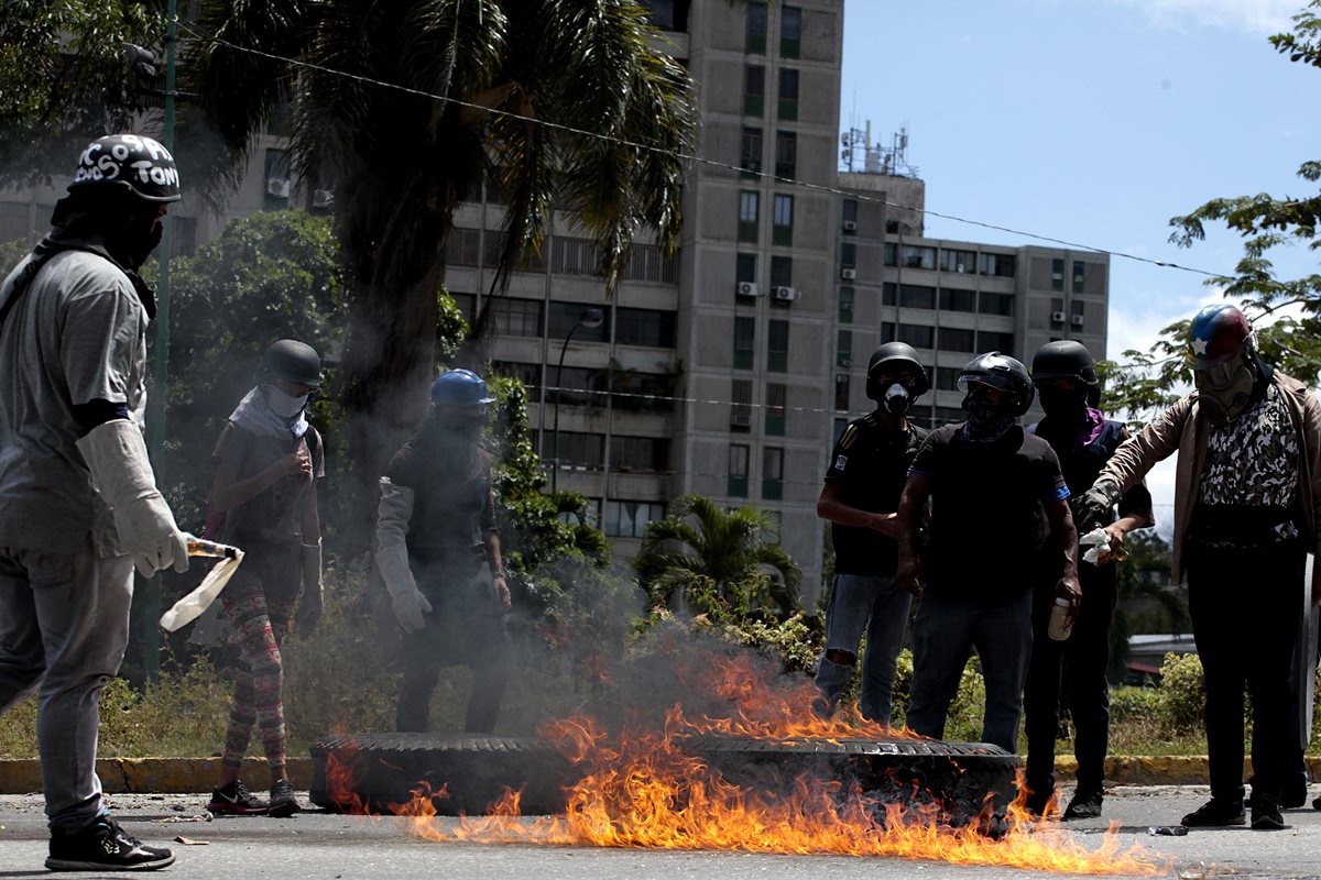 Manifestantes opositores se enfrentan a agentes de la Guardia Nacional Bolivariana mientras bloquean una calle en rechazo a las elecciones de la Asamblea Nacional Constituyente. (Foto Prensa Libre: EFE)