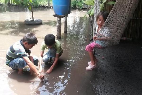 Niños juegan entre el agua que anega sus casas. (Foto Prensa Libre: Carlos Paredes)<br _mce_bogus="1"/>