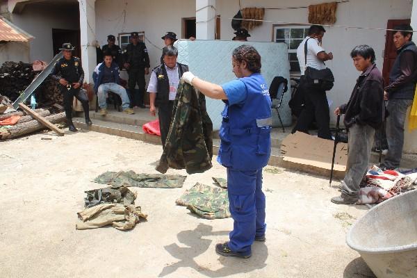 Una investigadora revisa uno de los uniformes verde olivo encontrados en un allanamiento efectuado en el cantón Paxtocá,  cabecera  de Totonicapán. (Foto Prensa Libre: Édgar Domínguez)