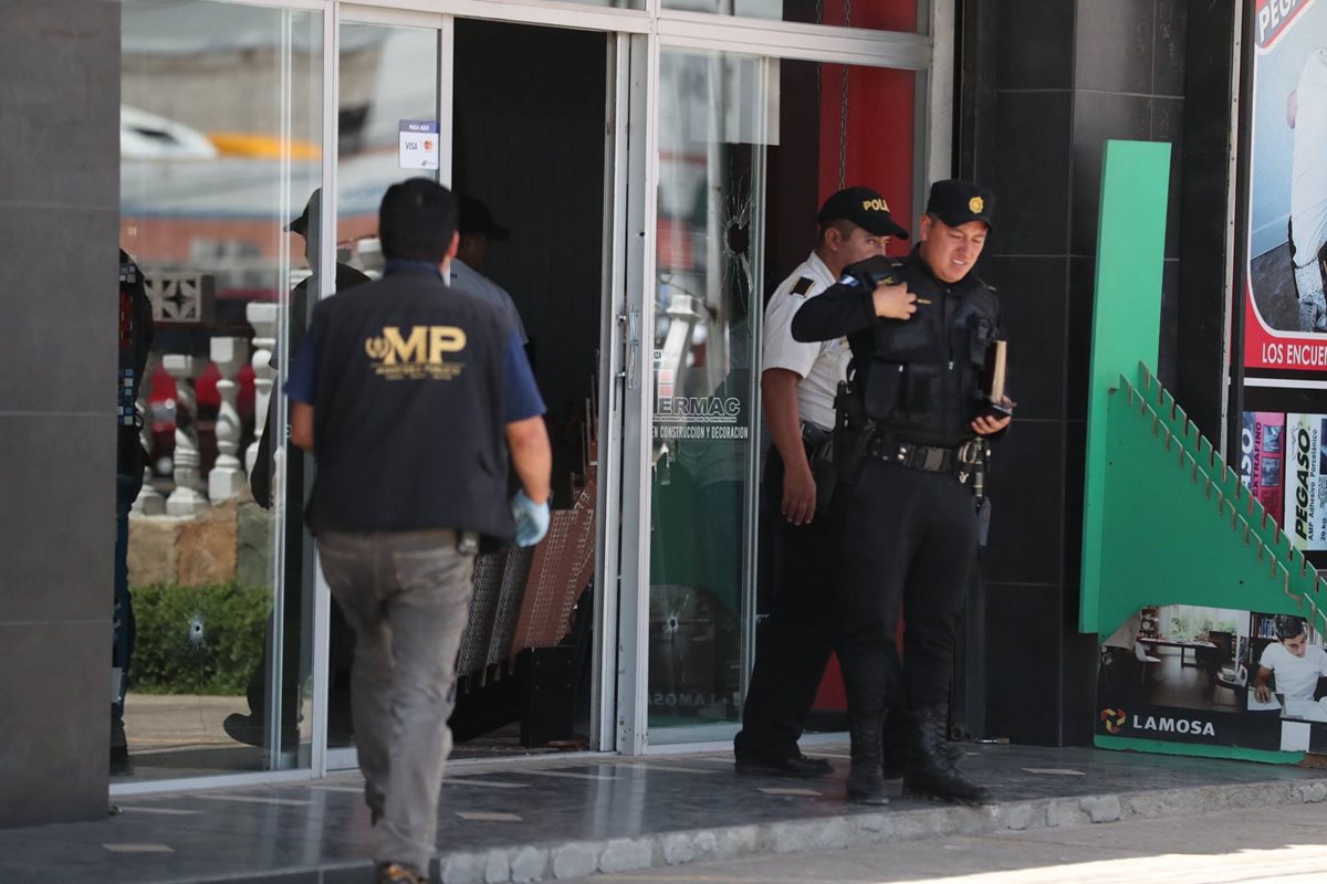 Un fiscal y dos policías revisan el frente del negocio ataque por dos sujetos armados en el Periférico, zona 8. (Foto Prensa Libre: Fred Rivera)