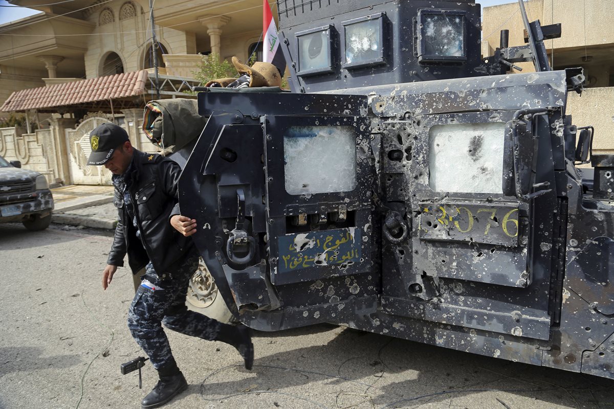 Un policía desciende de una patrulla que muestra múltiples impactos de bala en Mosul. (Foto Prensa Libre: AP)