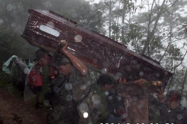 Soldados y vecinos cargan los féretros bajo la lluvia y entre el barro rumbo al cementerio. (Foto Prensa Libre: Mike Castillo)