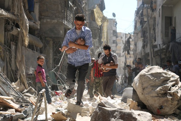 Sirios rescatan a bebés a través de los escombros de edificios destruidos en Alepo. (Foto Prensa Libre: AFP)