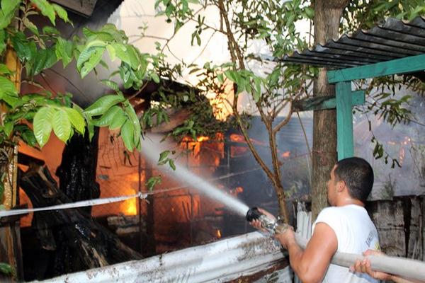 Socorristas y vecinos intentan sofocar el fuego en una vivienda en un barrio de la cabecera departamental en Retalhuleu. (Foto Prensa Libre: Rolando Miranda)<br _mce_bogus="1"/>