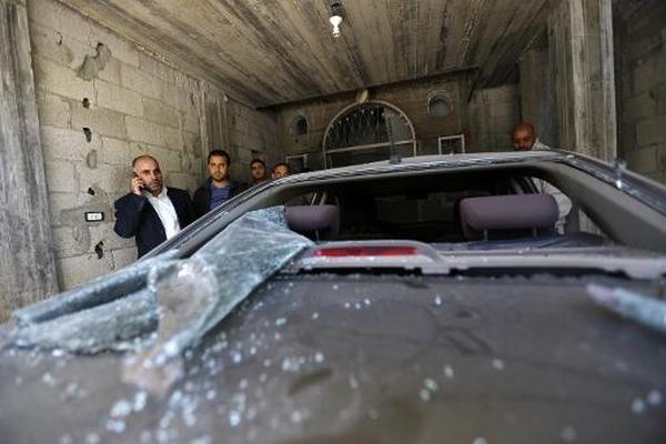 Un líder de Fatah en Gaza, Fayez Abu Eitta (izq), habla por teléfono  mientras observa los daños provocados contra su auto. (Foto Prensa  Libre: AFP)