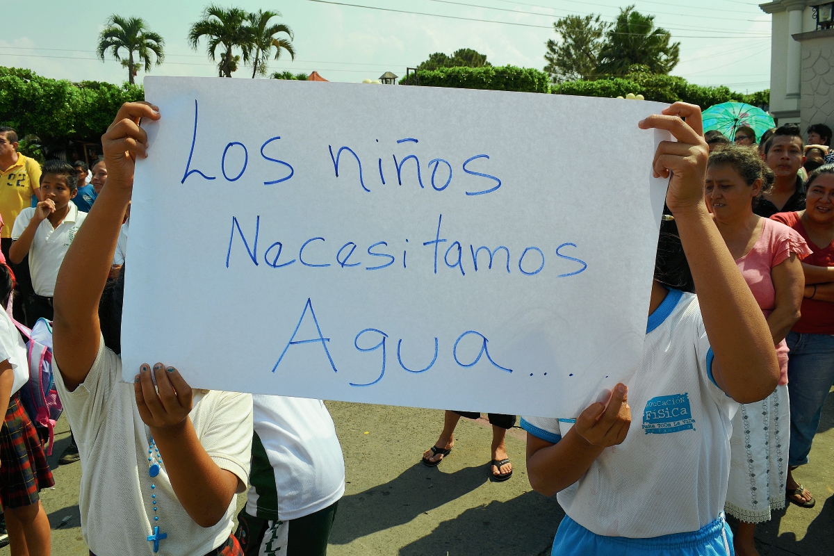 Dos niños  sostienen una pancarta durante la manifestación en San Felipe, Retalhuleu, en la que un grupo de vecinos exigió agua entubada. (Foto Prensa Libre: Jorge Tizol)