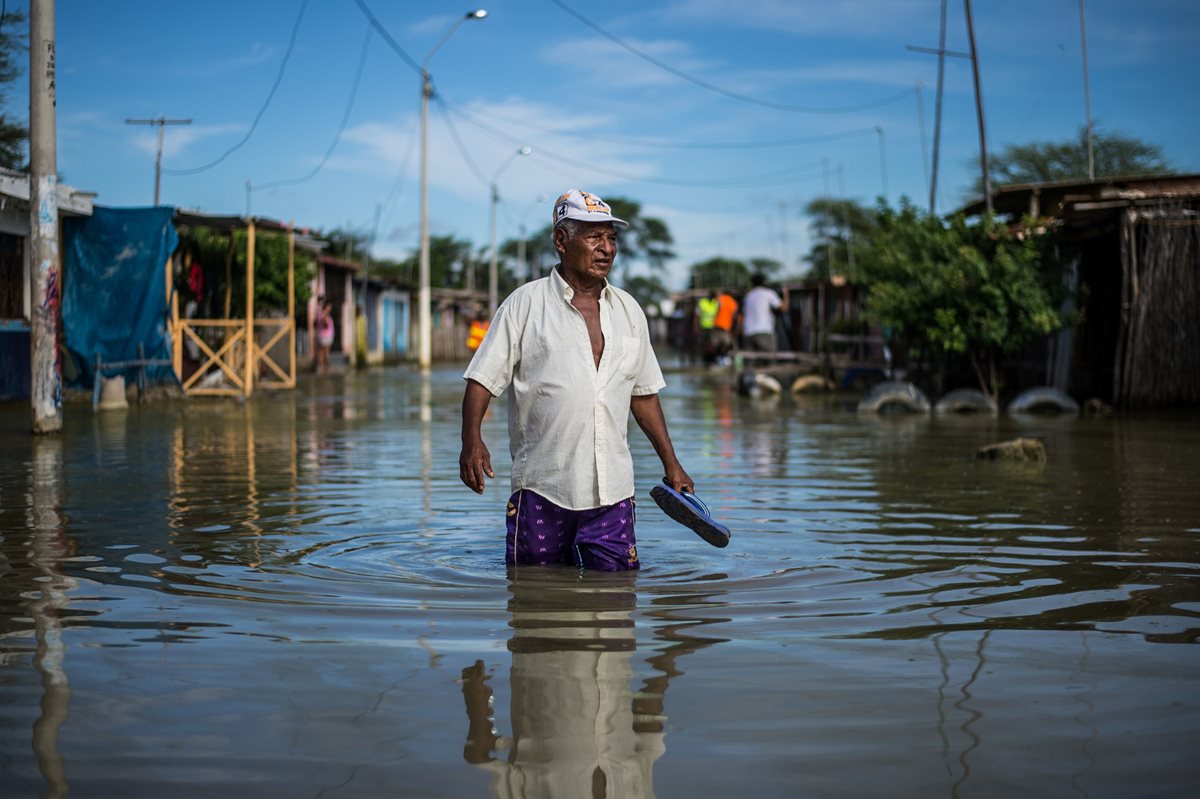 Un residente de Piura, Perú, es uno de los afectados por la inundación en la calle de "El Indio". (Foto Prensa Libre: AFP)