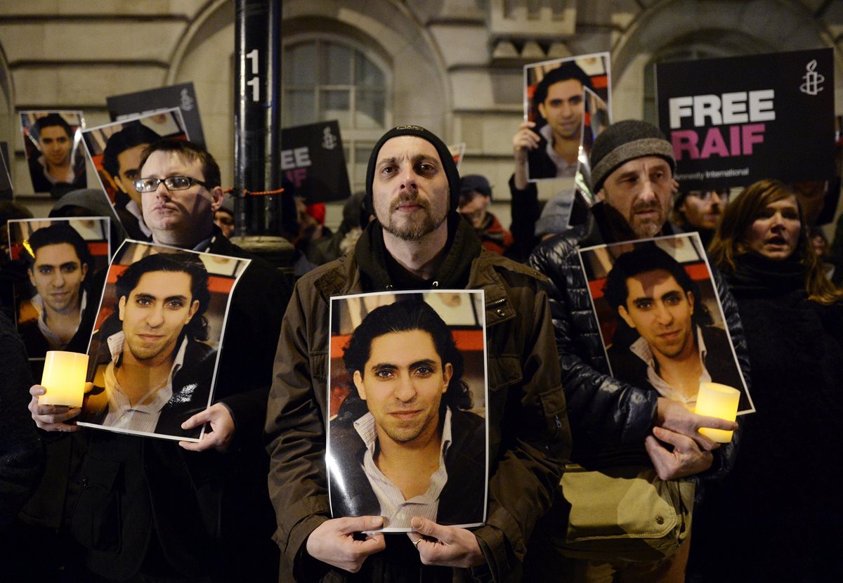 Seguidores de Raif Badawi sostienen su fotografía.(Foto Prensa Libre: EFE).