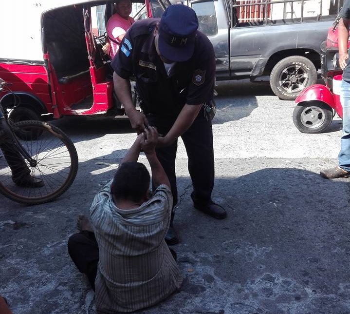 Un agente municipal retiene al indigente acusado de tirar basura en una calle de la zona 2 de Mazatenango. (Foto Prensa Libre: Cristian Icó)